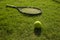 Tennis ball and racket on green grass field ground