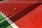 A tennis ball on the textured floor of a red court near the net after losing a match point