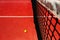 A tennis ball on the textured floor of a red court near the net after losing a match point