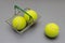 tennis balls in a miniature grocery basket