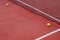 Tennis balls next to the net of a red hard surface tennis court