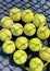 Tennis balls on the racket on hard court by the net. Tennis net shadows on tennis yellow balls.