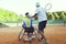 Tennis coach teaching a disabled player the backhand