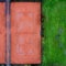 Tennis court with red gravel next to a lawn, abstract effect by