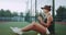 On the tennis court a sportiv woman prepare for a tennis game , sitting on the floor and relaxing.