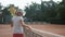 Tennis court, sports adolescent girl tennis player with racket touches net and walks along court after match under rain