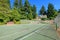 Tennis court wuth Large brown house exterior with summer garden.