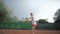 Tennis game, ambitious sport player adolescent girl hitting racket on ball at professional red court during tournament