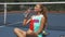 Tennis girl drinring water while relaxing on court