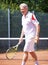 Tennis has always been his favorite past-time. A senior man walking on a clay court during a game of tennis.