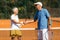 Tennis Instructor with Senior Woman in her 60s Handshaking after Having a Tennis Lesson on Clay Court