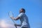 Tennis player with ball and racket against sky background prepares to serve ball