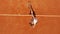 Tennis player hitting the ball on the red court. Summer sport concept. Top aerial view footage.