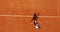 Tennis player hitting the ball on the red court. Summer sport concept. Top aerial view footage.