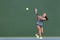 Tennis playing woman hitting ball on green hard court. Asian athlete girl returning serve with racket wearing skort and