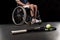 Tennis racquet with ball and disabled sportsman sitting in wheelchair behind