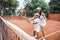 Tennis training for young kid. Full length shot of female tennis coach training little girl in sport club. Tennis instructor with