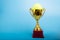 Tennis trophy, competition award cup on blue background, copy space