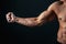 Tense arm clenched into fist, veins, bodybuilder muscles on a dark background, isolate