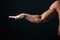Tense arm, veins, bodybuilder muscles on a dark background, isolate