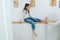 Tense girl sitting on a corridor shelf, her feet being tickled by her mom