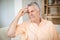 Tense senior man sitting on sofa in living room