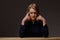 Tense young woman at the table on a dark background