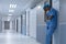 Tensed female surgeon with hand on head standing in the corridor at hospital