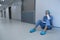 Tensed female surgeon sitting in the corridor of hospital