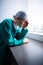 Tensed female surgeon standing at window