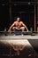 Tensing man lifting barbell in crossfit gym on dark sport club b
