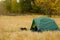 Tent in autumn forest, home for adventure and travel. Family outdoor recreation.