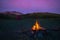 Tent and burning camp fire at dusk on the mountains. Summer adventures and exploration in the Alps. Selective focus on fire, color