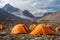 Tent camp and orange tents on the plateau of a mountain valley, the point of acclimatization of climbers before a high