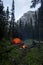 Tent and campfire wild camping in a forest with mountains