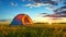 Tent in Field With Setting Sun. Hiking and outdoor recreation