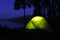 The tent glows in the night. Camping by the lake in a pine forest.