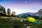 A tent glows under a moon night sky at twilight hour. Alps, Triglav National Park, Slovenia.