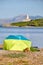 A tent with guarding dog on a beach with with Alcanada Lighthouse Faro de Alcanada in distance.