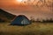 Tent on the hill beneath the mountains under dramatic sky