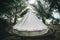 tent among palm trees on a tropical island. tent in the form of a Yurt. white modern wigwam made of fabric for spending the night