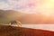 Tent shelter on lake shore at sunset - tranquil scene conveying calmness and freedom.