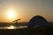 Tent with telescope stands on the hill under sunset