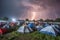 tents and shelters in the midst of a raging storm, with lightning bolts striking nearby