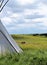 Tepee or Tipi with horses in the background on a Montana plain with blue sky