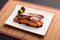 Teriyaki salmon plate on bamboo mat.