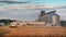 TERNOPIL REGION, UKRAINE - August 03, 2021: - large grain storage tanks and wheat field and combine CLAAS harvester, illustration