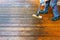 Terrace cleaning. Renovating a gray terrace using a hard scrub brush and green gel for renovating faded, gray boards - an