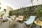 Terrace with fabric and wood hammocks, wicker furniture with fabric seats, decorative plants and stone floors