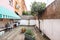 Terrace patio of a house on the ground floor with some plants and unvarnished acacia wood floors, white and green two-tone awning